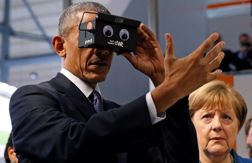 U.S. President Barack Obama tries virtual reality glasses as he and German Chancellor Angela Merkel (R) tour Hanover Messe Trade Fair in Hanover, Germany April 25, 2016. REUTERS/Kevin Lamarque